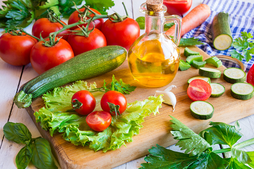 olive oil, cut tomato and fresh vegetables - healthy ingredients for cooking