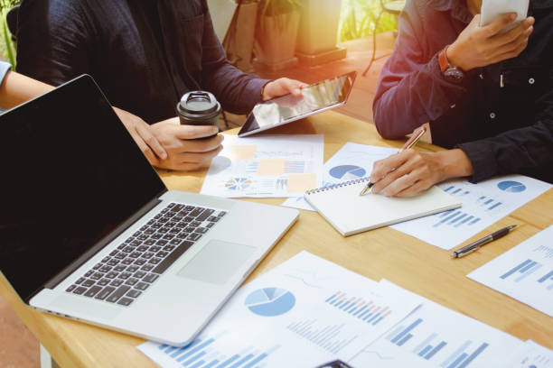 istock Business man using mobile phone and pen writing report, point to discuss the graph and down on economy. 895614602