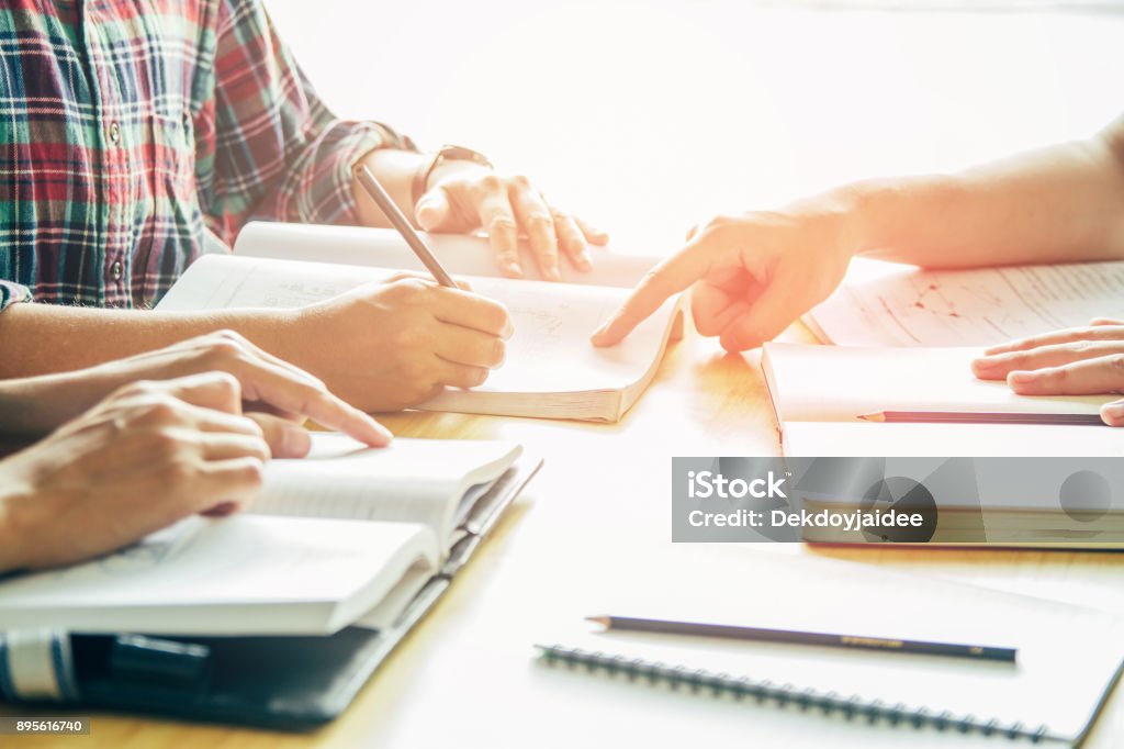 Asian young man,Homosexuality or woman sitting pointing studying examining. Tutor books with friends. Young students campus helps friend catching up and learning. People, learning, education Tutor Stock Photo