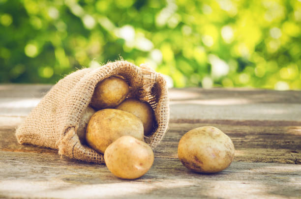 木製のテーブルの袋に若いジャガイモ - young potatoes ストックフォトと画像