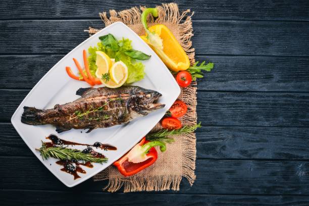 fish trout baked with vegetables and spices. on a wooden background. top view. free space for text. - m9 imagens e fotografias de stock