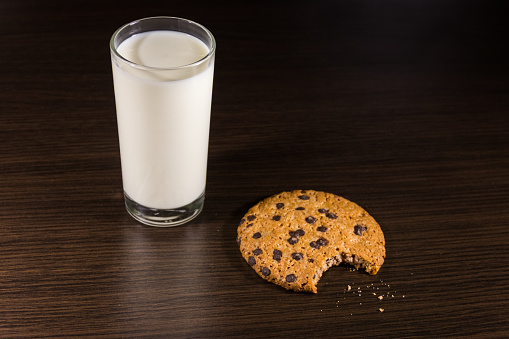 Homemade chocolate chips cookies with glass of milk on a rustic wooden table