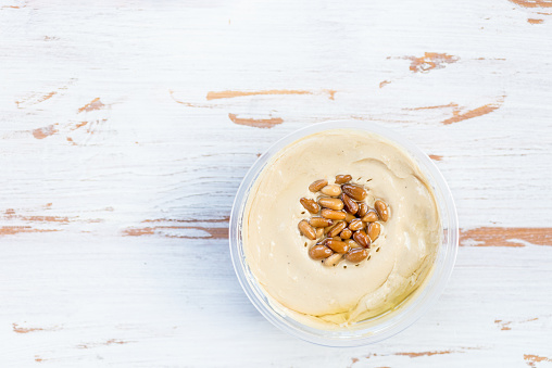 Classic Hummus made from Chickpeas with Pine Nuts on Top, Wooden Rustic Background, top view