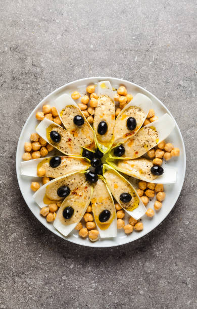 The leaves of Belgian endive with hummus, chickpeas and black olives. With strong olive oil of red pepperoncino. Modern delicious food for vegetarians and gourmets.