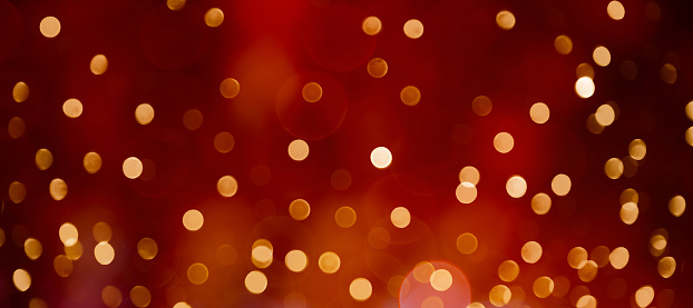 Colorful Festive Beautiful abstract Background with bokeh lights. Wide screen Holiday Texture for design flyers or web banner. Red Background with golden confetti.