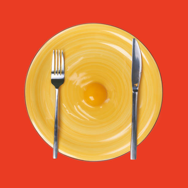 istock Egg's yolk on yellow plate with table setting, elevated view Against red Background 895646606