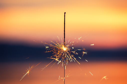 Bengal light on the sunset background, New Year with sparklers sparks on a sunset background.