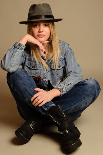 istock Girl in jeans, boots, hat and jacket sitting 895660694