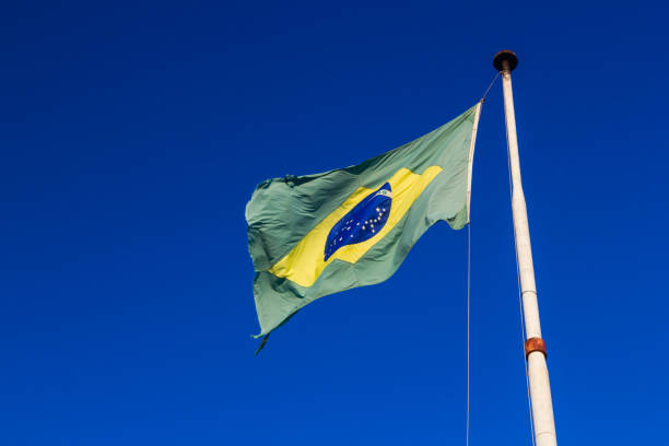 istock Brazilian flag on clear blue sky 895663326