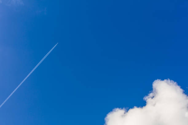 istock White plane flying high in the blue sky 895663792