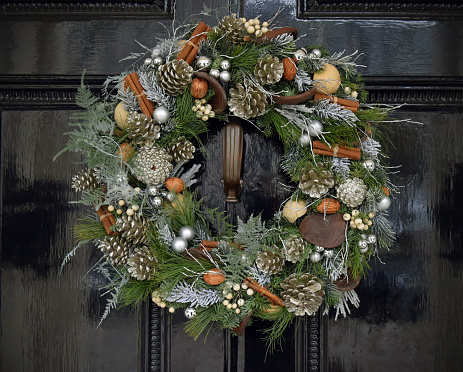 Traditional Christmas decorative yule wreath set on a Victorian black front door