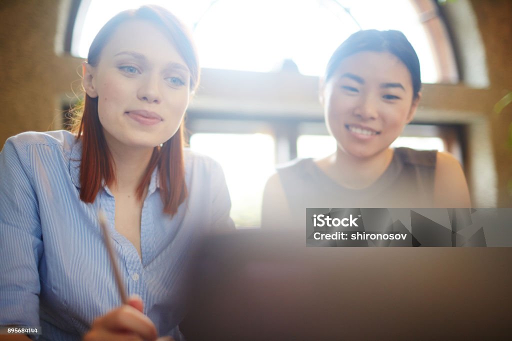 Watching business stream Young businesswoman and her colleague looking through curious information in the net while sitting in cafe Meeting Stock Photo