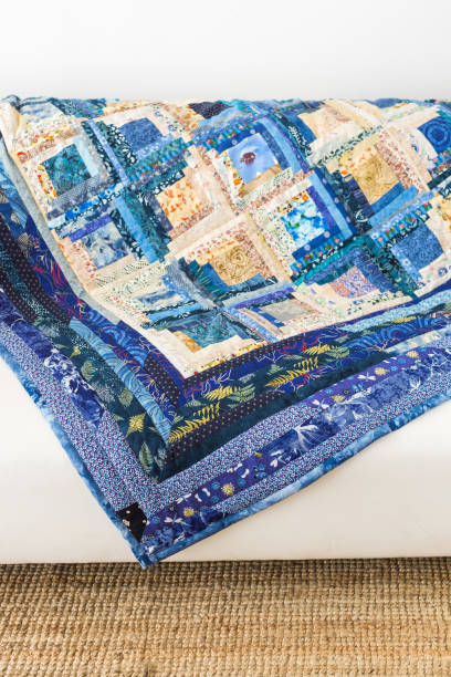 istock sewing, interior, patchwork, garment industry concept - magnificent blanket in light and dark blue shades, sewed of satin rags with absolutly different design, is laying on the sofa 895696494