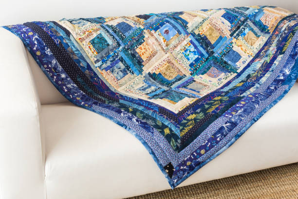 istock hobby, needlework, geometric, patchwork, interior, design concept - traditional blue and beige colored quilt created of patches with beautiful floral print covering minimalist white sofa 895696812
