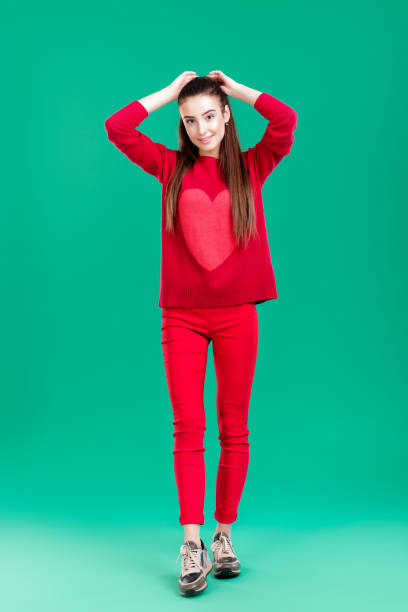 istock woman in red sweater on green background 895757050