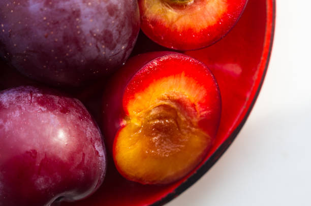 istock fresh plum fruit in the red saucer on white background 895798960
