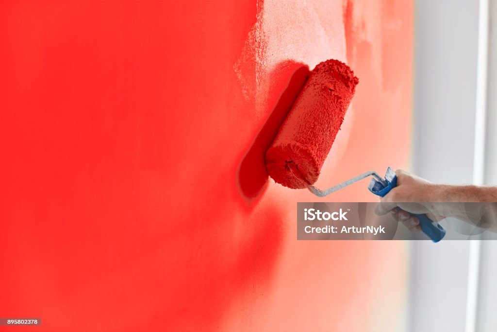 Parede de pintura mão masculino com rolo de pintura. Apartamento de pintura, renovando com tinta de cor vermelha - Foto de stock de Pintar royalty-free