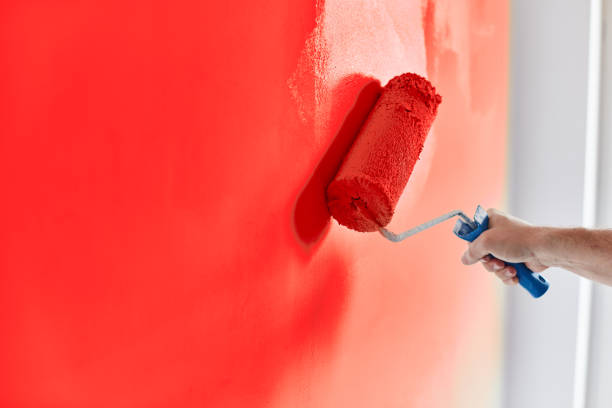 male hand painting wall with paint roller. painting apartment, renovating with red color paint - pintar parede imagens e fotografias de stock