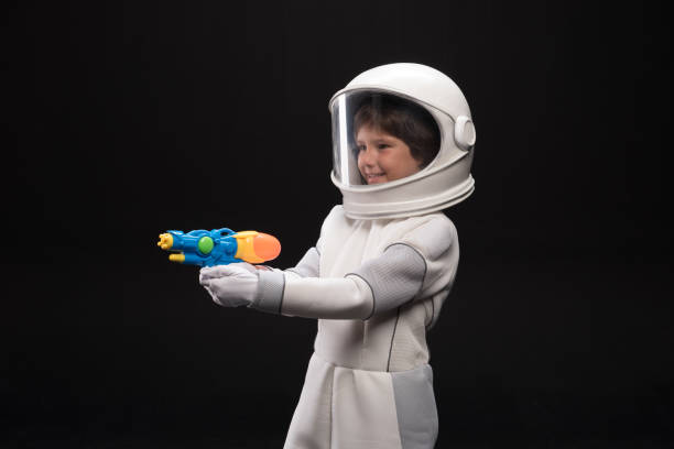 istock Cheerful cosmonaut is playing with handgun 895813876