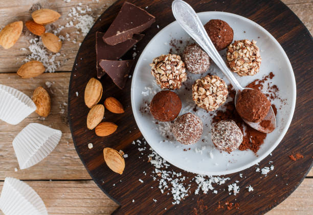 istock Prepare assorted dark chocolate truffles with cocoa powder, coconut and chopped almonds closeup. Homemade candy. Selective focus 895854436