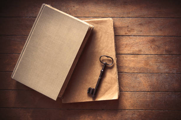Vintage key and old books on wooden table. Photo in old image color style