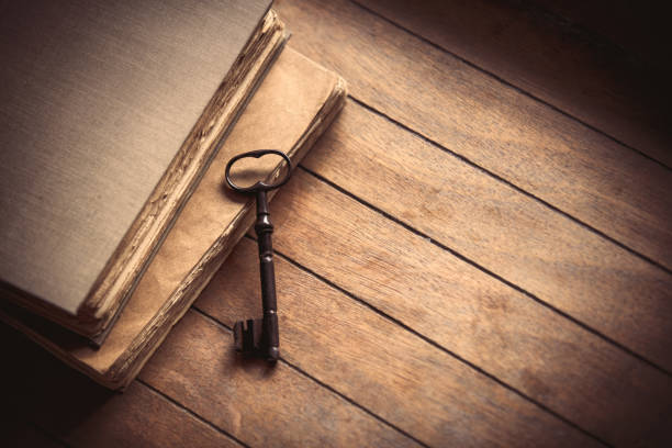 istock Vintage key and old books on wooden table. 895856372