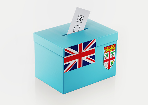 Ballot box textured with Fijian flag. Isolated on white background. A vote envelope is entering into the ballot box. Horizontal composition with copy space. Great use for referendum and presidential elections related concepts. Clipping path is included.