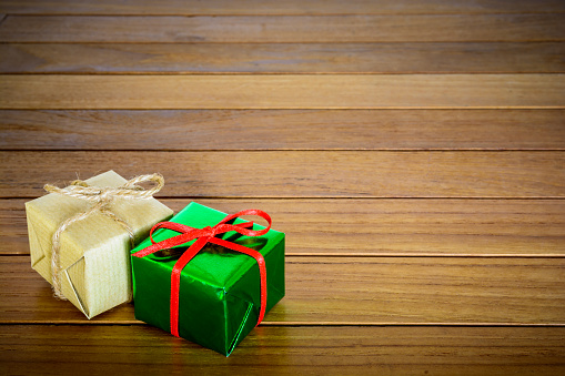 Metallic green and brown paper gift packages on a wooden background.