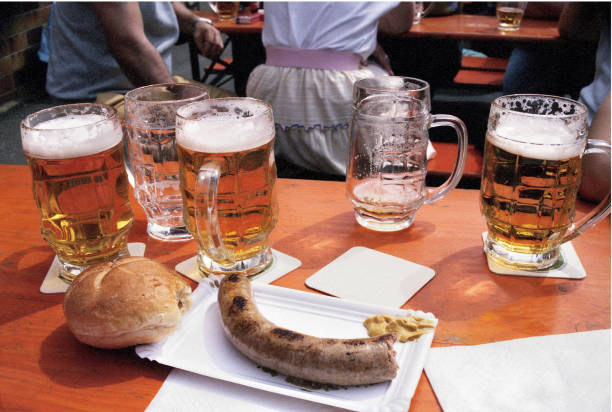 Lifestyle...In a German beer hall, this close up shows several beer steins, bread, and a plate of sausage sitting  on a table top...{Scanned from a slide}.