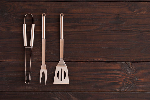 kitchen tongs, fork for meat and spatula on a wooden background
