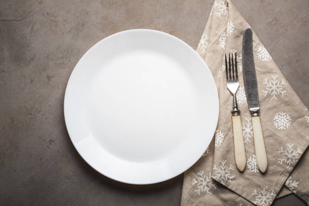 istock Empty plate with cutlery and beige towel with snowflakes on the stone table. Overhead view 895908306