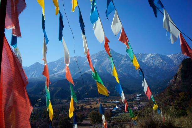 Colorful Tibetan prayer flags flutter ancient prayers into serene mountain wind at top of high hill on blue sky background, symbolizing spiritual energy peaceful tranquility