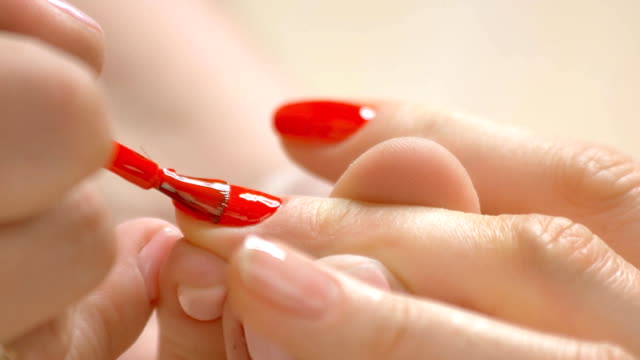 Red varnish applying on nails.