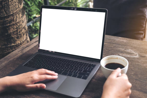 istock Mockup image of a woman using laptop with blank white screen while drinking coffee on wooden table at outdoor 895945012