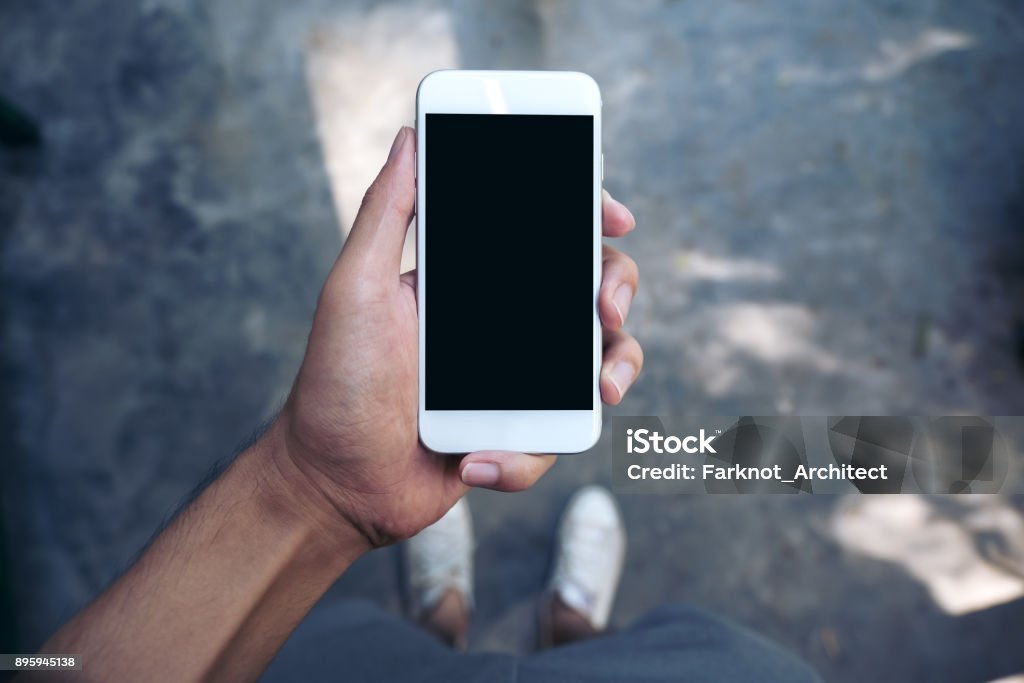 Mock-up Bild eines Mannes Hand halten weiße Handys mit leeren schwarzen Bildschirm beim stehen auf Beton Boden Polieren - Lizenzfrei Telefon Stock-Foto