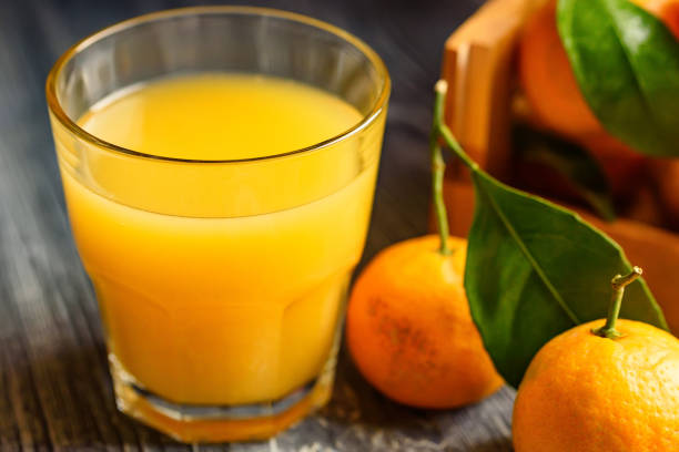 istock Glass of fresh juice and mandarins on table 895952748
