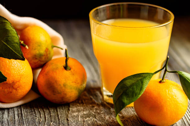 istock Glass of fresh juice and mandarins on table 895952812