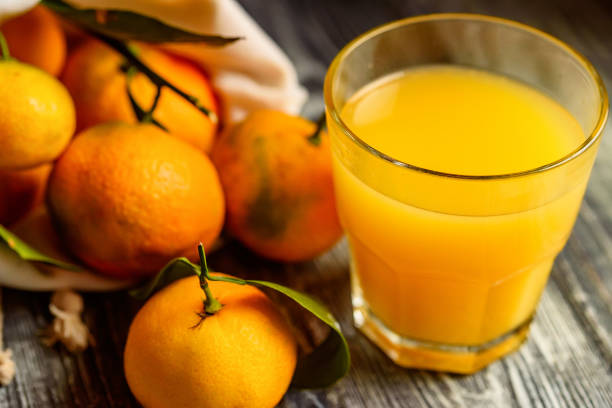 istock Glass of fresh juice and mandarins on table 895952832