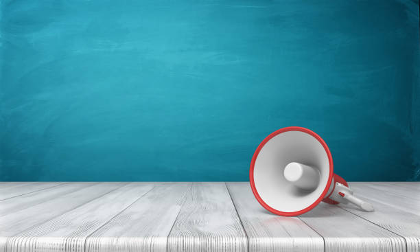 istock 3d rendering of a single red and white megaphone lying down on a wooden desk on blue background 895952948