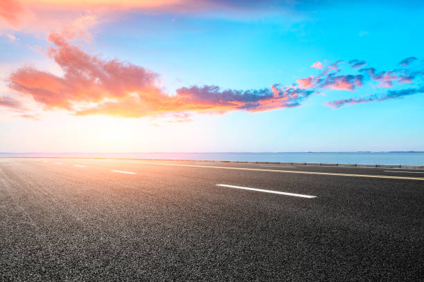 leere asphalt straßen- und blaue meer natur-landschaft bei sonnenuntergang - street side view summer nature stock-fotos und bilder