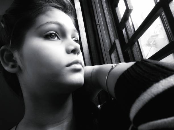 istock girl looking away with blank expression sitting near window 896022724