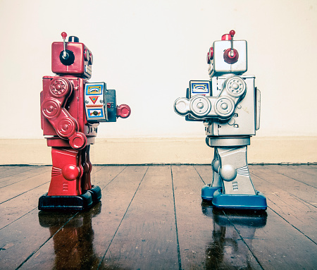 two retro robots face off with ray guns on a wooden floor with reflection