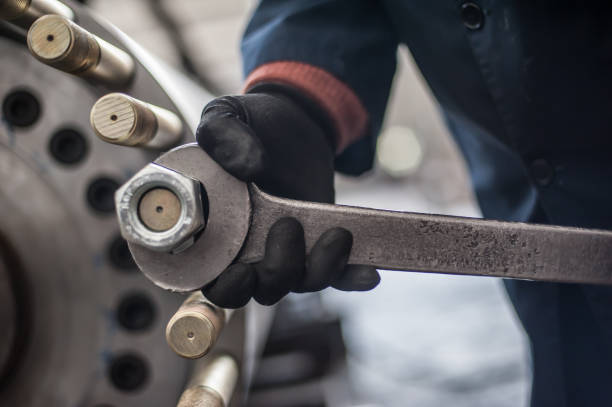 mechanika wkręca dużą śrubę z dużym i ciężkim kluczem do kluczy - screw wrench zdjęcia i obrazy z banku zdjęć