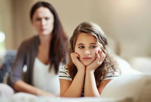 Cropped shot of a young girl being reprimanded by her mother at home