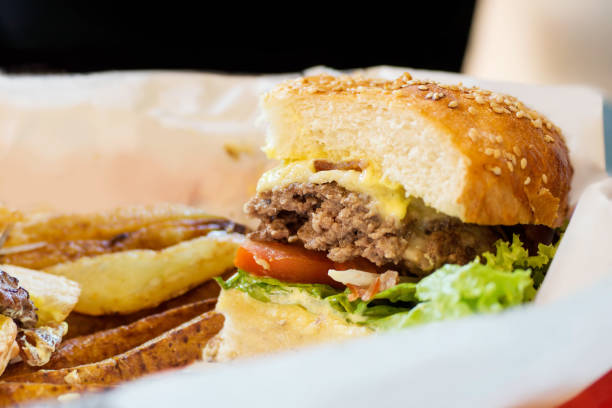 istock Junk food background: Half blue cheese burger with beef and vegetables on white paper with golden potato 896032796