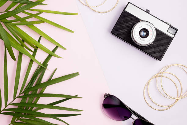 Boho style travel mock up: palm leaves, vintage camera, golden bangles and sunglasses on colorful pink and purple background stock photo