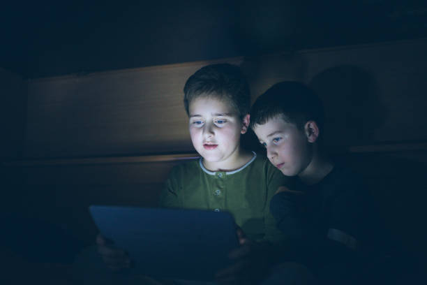 istock Kids secretly reading playing with digital tablet 896039920