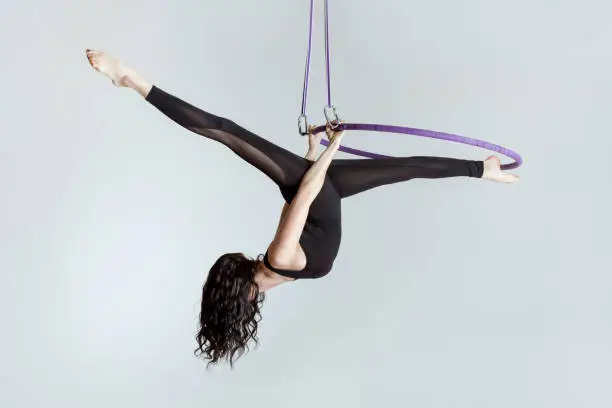 Woman aerial acrobat on the ring shows tricky tricks.