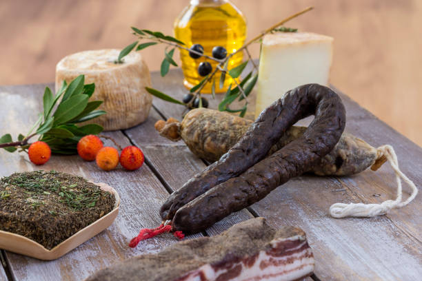several variety of traditional Corsican charcuterie with an olive branch and black olives on wooden background stock photo
