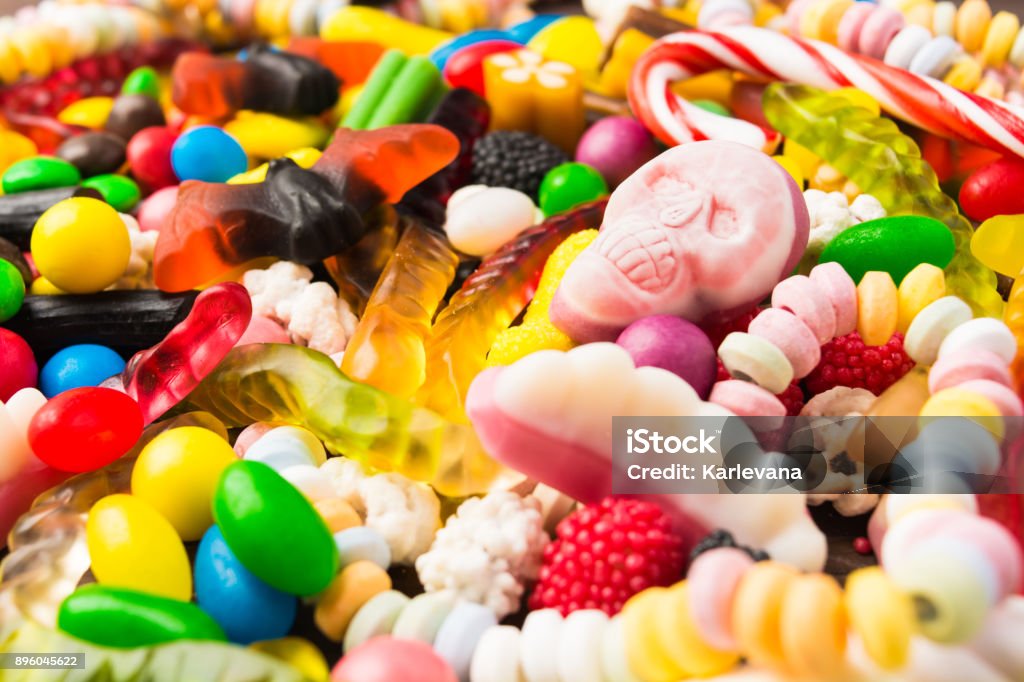 Different candies with closeup pink skull for trick or treat Different candies with closeup pink skull for trick or treat, selective focus Candy Stock Photo